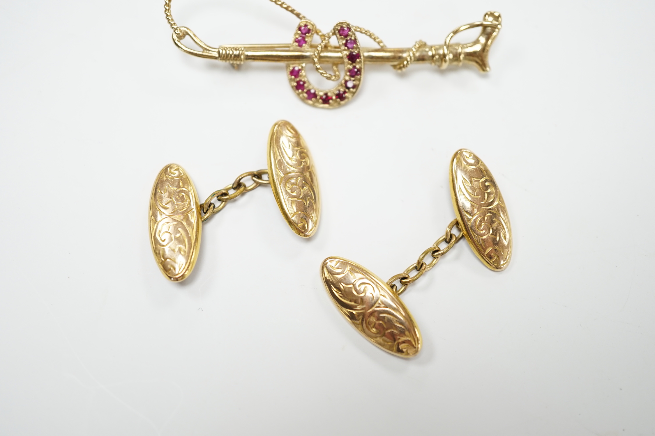 A pair of George V engraved 9ct gold oval cufflinks and a yellow metal and ruby cluster set horseshoe and riding crop bar brooch, gross weight 7.1 grams.